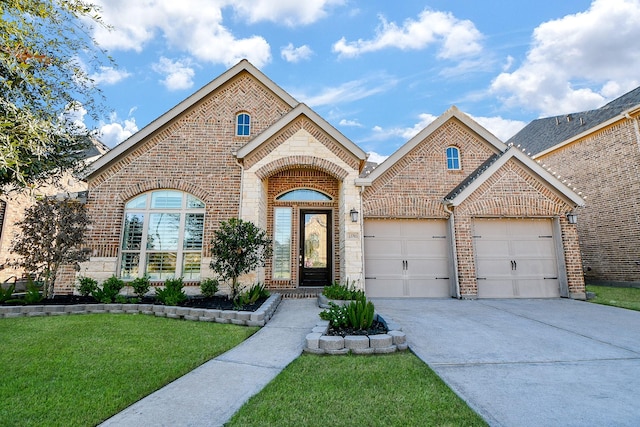 french country home featuring a front lawn, an attached garage, brick siding, and driveway