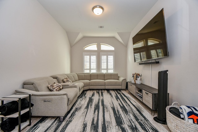 living area with visible vents, wood finished floors, and vaulted ceiling