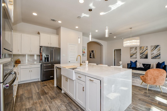 kitchen featuring visible vents, arched walkways, a sink, high end refrigerator, and stainless steel dishwasher