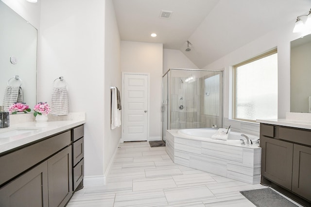 bathroom with visible vents, a garden tub, vaulted ceiling, two vanities, and a stall shower