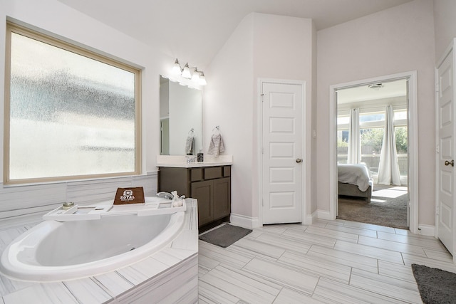 full bathroom featuring vanity, a garden tub, baseboards, and ensuite bathroom