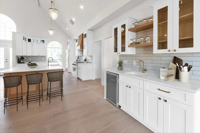 kitchen featuring light wood finished floors, beverage cooler, a breakfast bar, high end range, and a sink