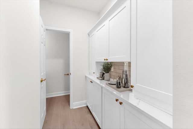 bar featuring backsplash, light wood-style flooring, and baseboards