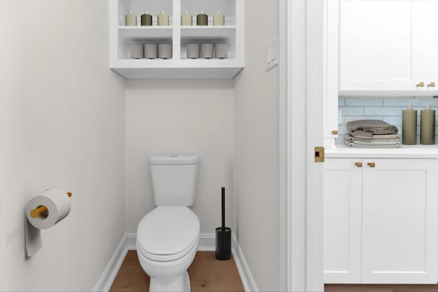 bathroom with tasteful backsplash, toilet, and baseboards