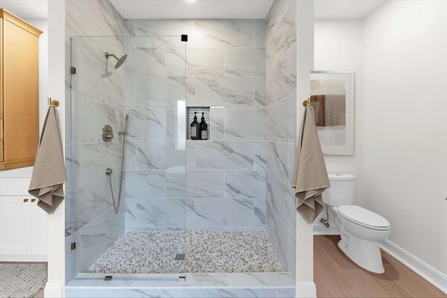 bathroom featuring a marble finish shower, baseboards, toilet, and wood finished floors