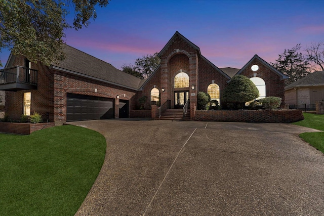 french provincial home featuring a balcony, concrete driveway, a front lawn, a garage, and brick siding