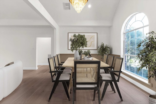 dining space with a wealth of natural light, visible vents, an inviting chandelier, and wood finished floors