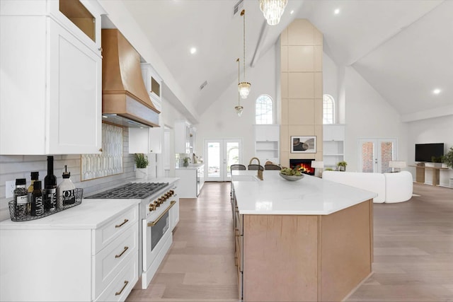 kitchen with custom exhaust hood, french doors, open floor plan, and light wood-type flooring