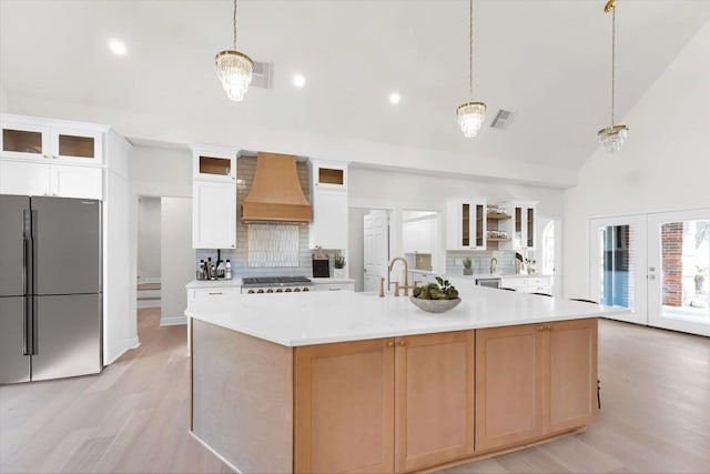 kitchen featuring visible vents, custom exhaust hood, light wood-style flooring, freestanding refrigerator, and light countertops