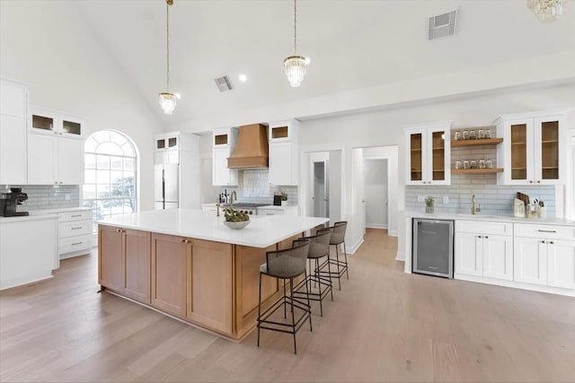 kitchen featuring visible vents, light wood finished floors, custom exhaust hood, and freestanding refrigerator