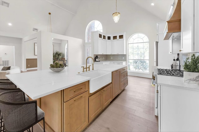 kitchen featuring visible vents, a sink, a kitchen breakfast bar, open floor plan, and decorative backsplash