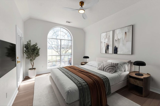 bedroom featuring visible vents, baseboards, lofted ceiling, light wood-style floors, and a ceiling fan