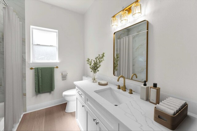 bathroom with vanity, wood finished floors, baseboards, curtained shower, and toilet