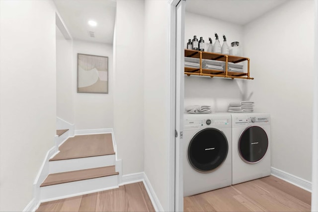 laundry area featuring baseboards, light wood-style floors, washing machine and dryer, and laundry area