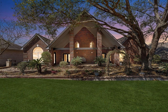 view of front of house with a lawn and brick siding