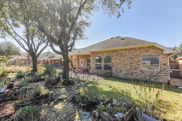 back of property featuring fence, brick siding, roof with shingles, and a lawn