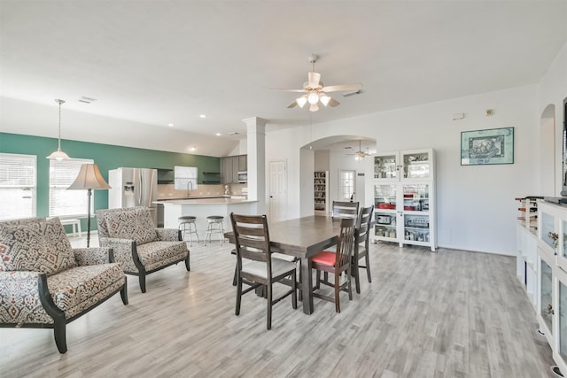 dining room with lofted ceiling, light wood-style floors, arched walkways, and ceiling fan