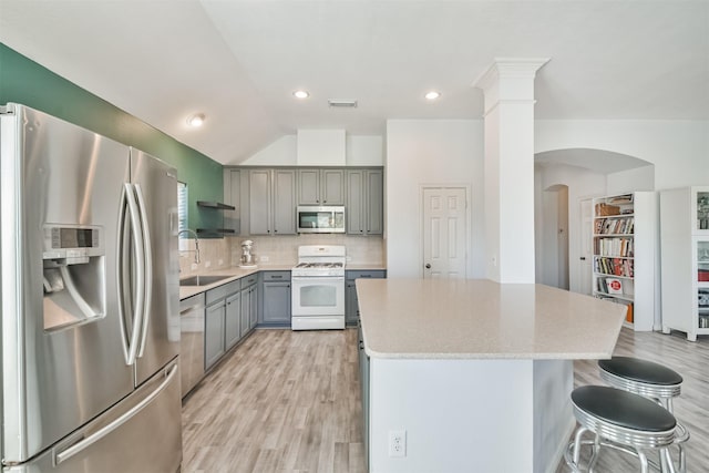 kitchen with visible vents, a kitchen island, gray cabinets, appliances with stainless steel finishes, and a sink