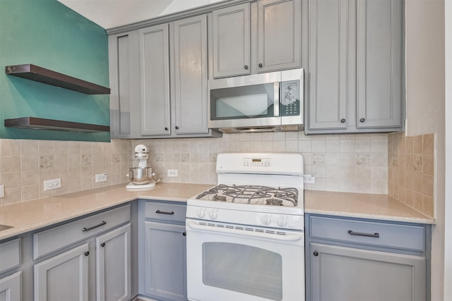 kitchen featuring stainless steel microwave, gray cabinets, white gas range oven, and open shelves