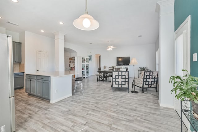 kitchen featuring ceiling fan, light countertops, gray cabinets, freestanding refrigerator, and arched walkways