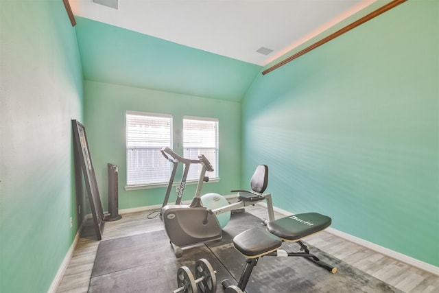 workout room with vaulted ceiling, wood finished floors, baseboards, and visible vents