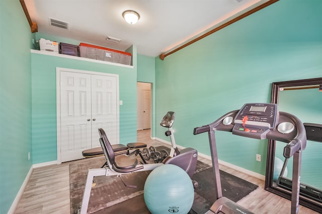 workout room with wood finished floors, visible vents, and baseboards