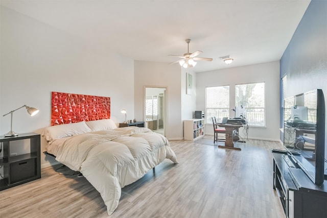 bedroom with light wood-style flooring, a ceiling fan, and baseboards