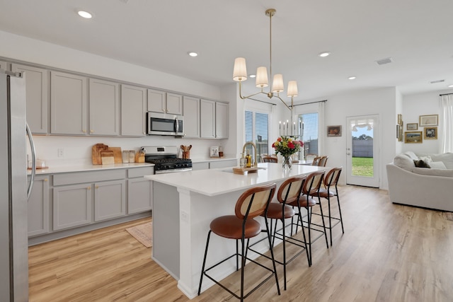 kitchen with light wood-type flooring, visible vents, gray cabinetry, stainless steel appliances, and light countertops