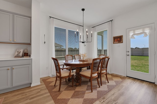 dining space with baseboards, light wood-style floors, and an inviting chandelier