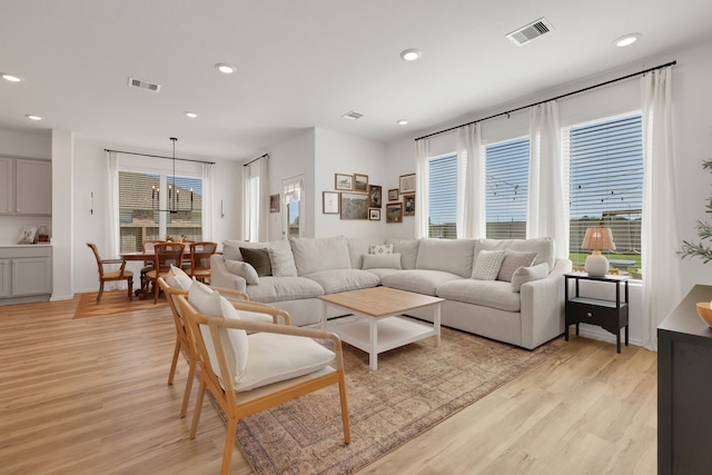 living area featuring a wealth of natural light, visible vents, and light wood-style floors