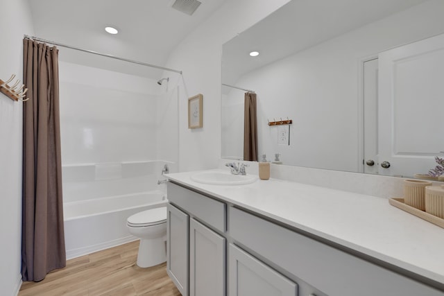 bathroom with visible vents, toilet, wood finished floors, shower / tub combo, and vanity