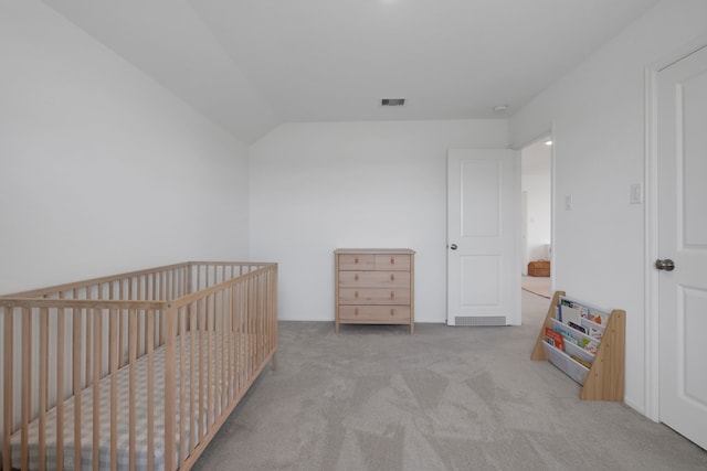 carpeted bedroom with visible vents, a crib, and vaulted ceiling