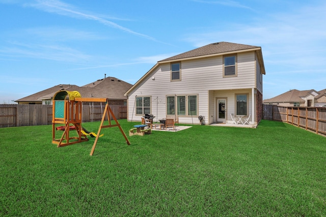 rear view of house featuring a patio, a playground, a yard, and a fenced backyard