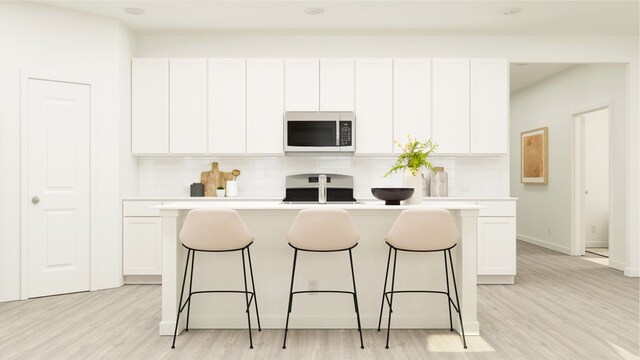3012 Ruby Ridge Dr, Katy, TX 77493 - kitchen with a kitchen bar, white cabinets, tasteful backsplash, and a kitchen island