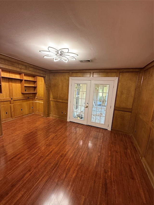 unfurnished living room with wood finished floors, visible vents, french doors, and a textured ceiling