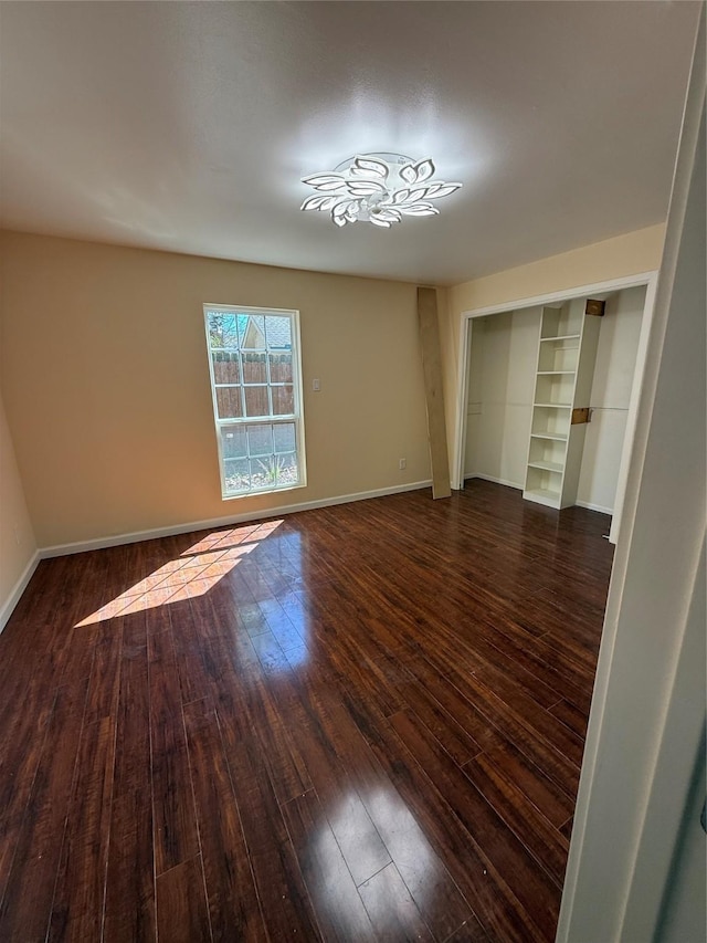 unfurnished bedroom with a closet, dark wood-type flooring, and baseboards