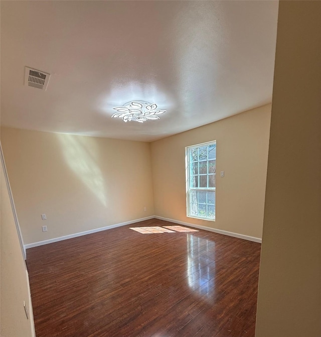 empty room with visible vents, baseboards, and dark wood-style floors