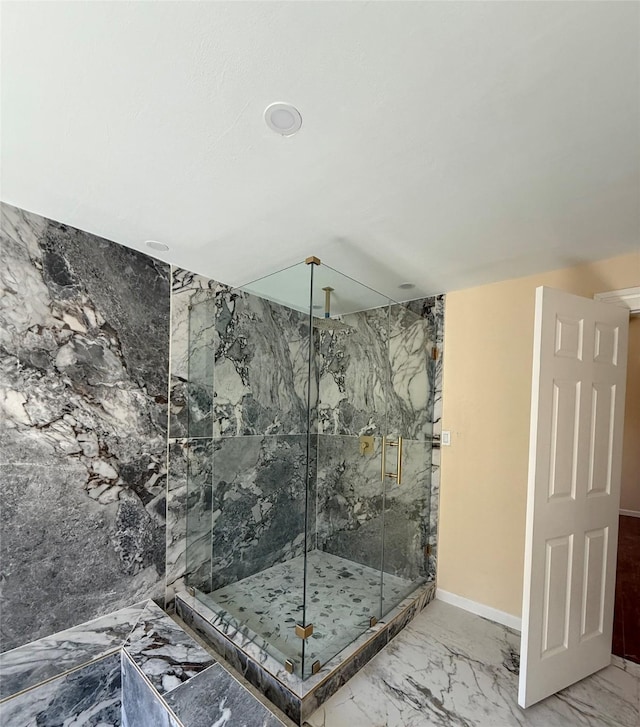 full bath with a marble finish shower, baseboards, and marble finish floor