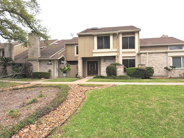 view of front facade with brick siding, a chimney, and a front lawn