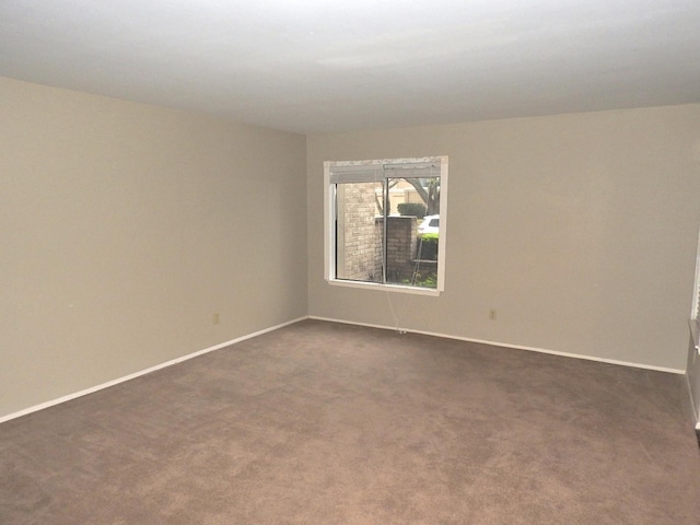 unfurnished room featuring dark colored carpet and baseboards