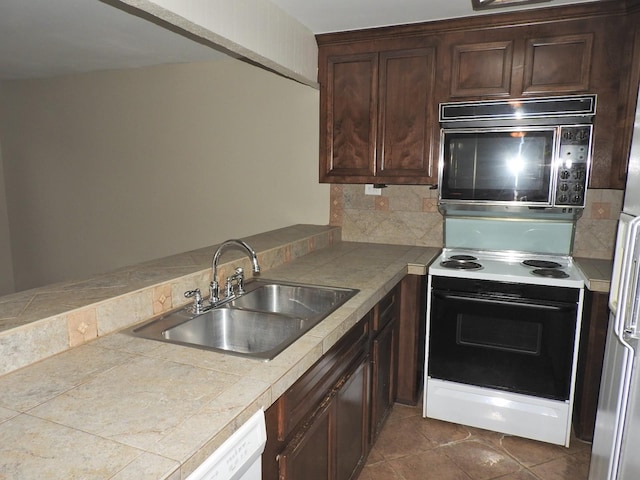 kitchen featuring range with electric cooktop, a sink, dark brown cabinetry, black microwave, and backsplash