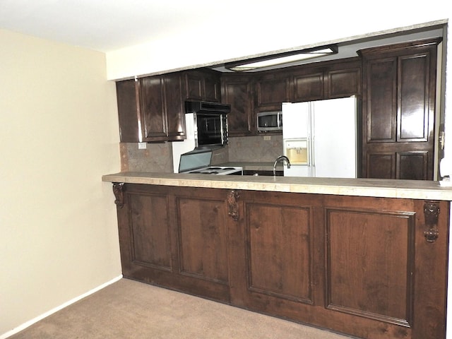 kitchen featuring electric range oven, dark brown cabinetry, white fridge with ice dispenser, stainless steel microwave, and backsplash