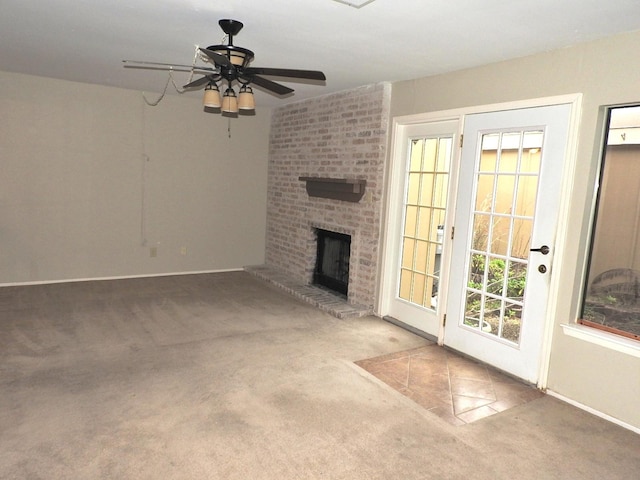 unfurnished living room with a brick fireplace, ceiling fan, and carpet floors