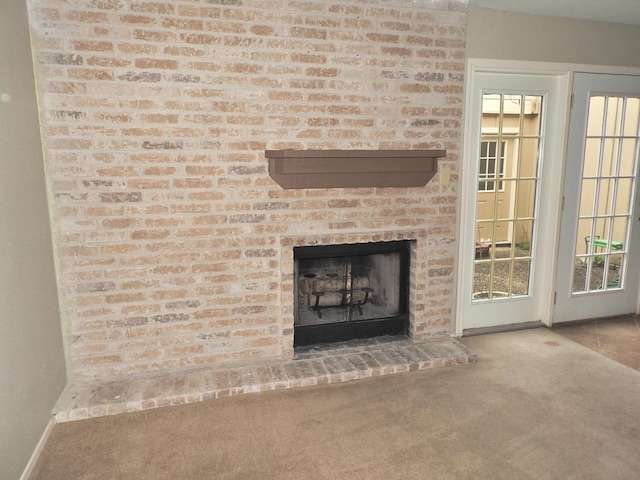 unfurnished living room featuring carpet flooring, a brick fireplace, and baseboards