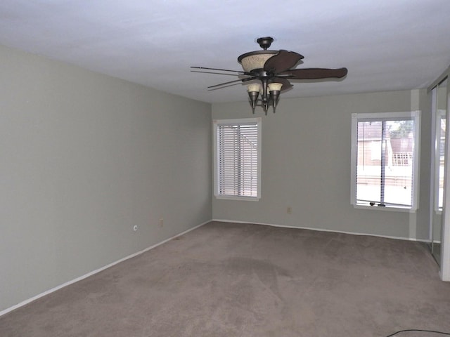 carpeted empty room featuring baseboards and ceiling fan