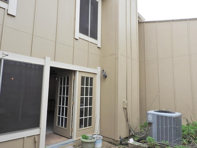 view of exterior entry with board and batten siding and central AC