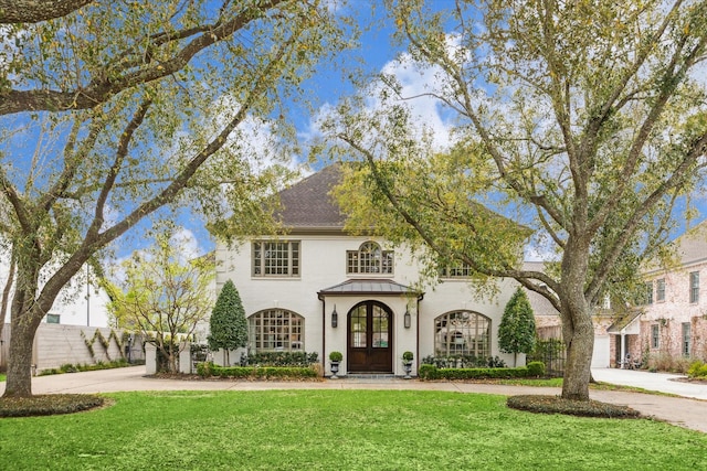 view of front of house featuring a front yard, driveway, a standing seam roof, french doors, and metal roof