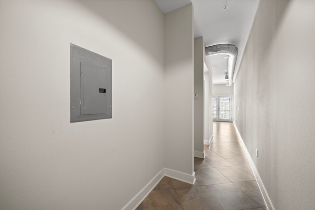 hall featuring tile patterned floors, electric panel, and baseboards