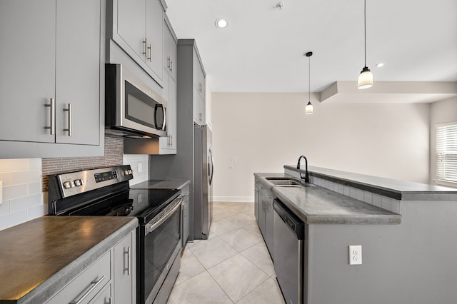 kitchen with dark countertops, tasteful backsplash, light tile patterned floors, stainless steel appliances, and a sink