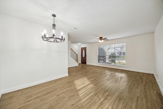 unfurnished living room with visible vents, baseboards, stairway, light wood-style flooring, and ceiling fan with notable chandelier